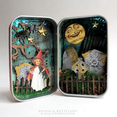 an open tin box with a halloween scene inside