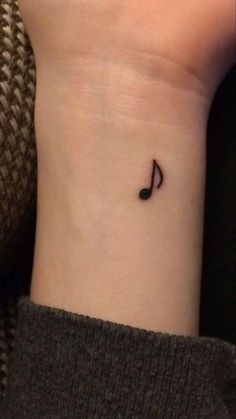 a small music note tattoo on the left side of the wrist, with black ink