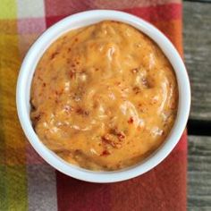 a white bowl filled with sauce on top of a checkered table cloth