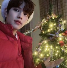 a young man wearing a santa hat next to a christmas tree