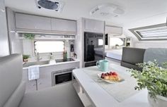 the interior of an rv with kitchen and living room area in white, grey and black