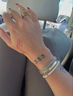 a woman's hand with a small tattoo on her left wrist in a car