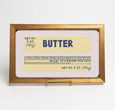 a sign that says butter on it in front of a white background with gold frame