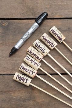 several wooden sticks with writing on them and one pen next to it that says marshmallows