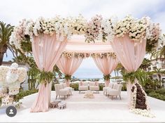 an outdoor wedding setup with pink drapes and white flowers