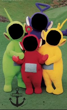 four stuffed animals standing next to each other on a green grass covered golf course with an anchor in the background