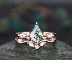 a green and white stone ring sitting on top of a rock with diamonds around it