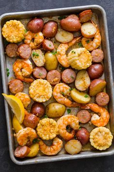 a pan filled with potatoes and shrimp next to a slice of lemon on the side