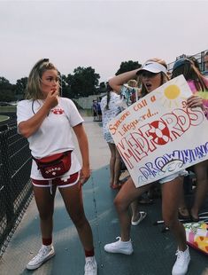 two girls are holding a sign and posing for the camera