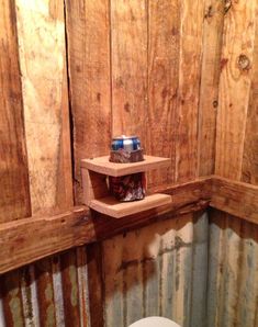 a toilet in a small room with wooden paneling on the walls and a shelf above it