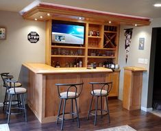 a bar with three stools in front of it and a television on the wall