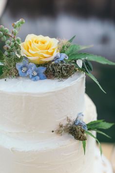 a white wedding cake with blue and yellow flowers on top