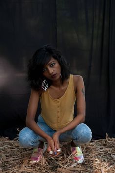 a woman sitting on the ground with her hands in her pockets