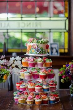 there are many cupcakes on the table and one is stacked high with flowers