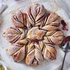 a white plate topped with pastries covered in powdered sugar next to a spoon