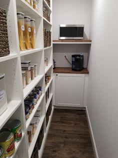 a pantry with white shelving and wooden shelves filled with food items, including pasta