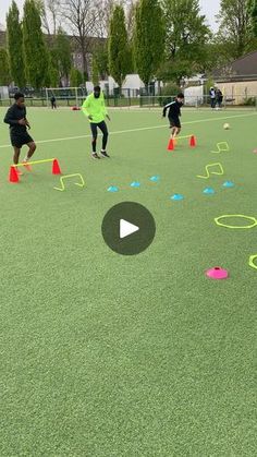 several people are playing frisbee on an artificial field with cones and markers in the foreground