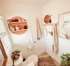 there is a bathroom with towels hanging on the wall and plants in pots next to the door