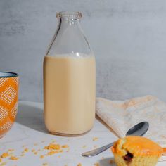 a bottle of milk next to a muffin on a table