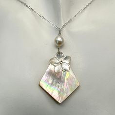 This yellow mother of pearl diamond shaped pendant has gorgeous tones of pinks, purples and light greens. Sadly it is the only one I have. It is topped with a carved mother of pearl plumeria with a small Swarovski yellow crystal in the center. A lustrous oval freshwater pearl tops this pendant. It is about 2 1/4 inches from the top of the sterling silver wire wrap to the bottom of the pendant. The necklace can come in many lengths. If you don't see a length you need please message me. To see mor Silver Mother Of Pearl Shell Necklace As Gift, Pearl White Mother Of Pearl Shell Necklace Gift, Pearl White Mother Of Pearl Shell Necklace As Gift, White Mother Of Pearl Pendant Shell Necklace, Mother Of Pearl Gemstone Pendant, Mother Of Pearl Gemstone Pendant Jewelry, Mother Of Pearl Shell Necklace Gift, Elegant White Abalone Shell Jewelry, Unique Mother Of Pearl Jewelry With Pearl Pendant