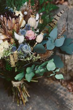 a bouquet of flowers sitting on top of a wooden table next to leaves and branches