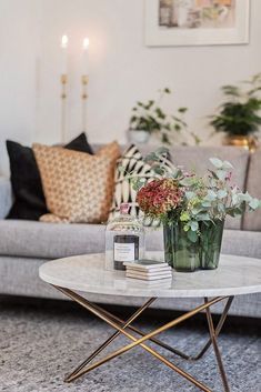 a living room with a couch, coffee table and flowers on the end tables in front of it