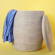 a large woven basket with a blue cloth on top and a round lid sitting in front of a yellow background