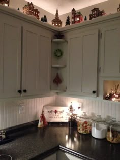 a kitchen with white cabinets and black counter tops is lit up by the lights on the ceiling