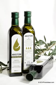 two bottles of olive oil next to an olive branch