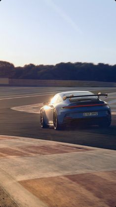 a blue sports car driving on a race track with the sun shining through the windshield