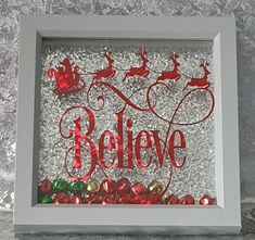 a white frame with red and green ornaments in it that says believe on the side