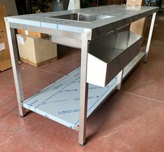 a stainless steel table with an open drawer on it's side in a warehouse