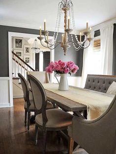 a dining room table with chairs and a large clock on the wall above it,