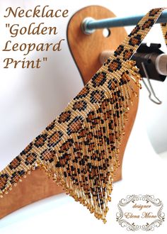 a close up of a piece of beaded fabric on a stand with the words necklace'golden leopard print '