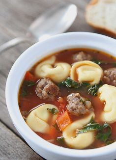 a close up of a bowl of soup with meatballs and veggies in it