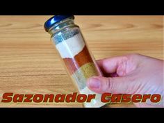 a hand holding a salt shaker over a wooden table with the words sazonnado casero on it