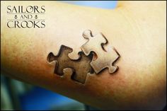 a person with a piece of puzzle tattoo on their arm that says sailors and crooks