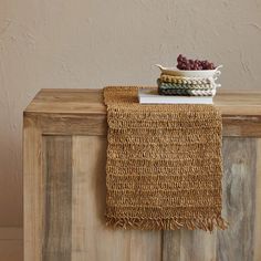 a table with a bowl of grapes on top of it next to a wooden cabinet