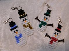 three beaded keychains with snowmen on them sitting on a white blanket