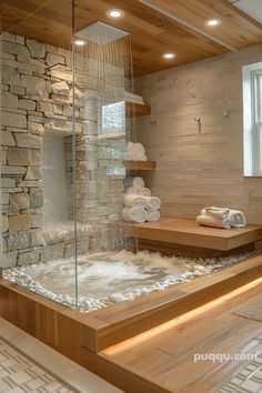 a bathroom with stone walls and wooden flooring, along with a glass enclosed sauna