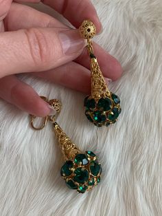 "These are vintage mid-century clip on earrings. They are in a gold tone metal that is bright and shows no signs of wear or tarnish. The base of the earrings have round shape emerald tone rhinestones that form a sphere. The earrings are in excellent condition. Measurements: Length: 2\" | Width: .75\" Unless otherwise stated all vintage items are used and may have minor to moderate wear or discoloration considering the age of the item. Most items have been hand washed, spot cleaned, or profession Vintage Jeweled Drop Earrings, Costume Jewelry Jeweled Clip-on Earrings For Formal Occasions, Costume Jewelry Style Jeweled Clip-on Earrings For Formal Events, Costume Jewelry Clip-on Earrings With Jewels For Formal Events, Formal Jeweled Clip-on Costume Jewelry Earrings, Formal Jeweled Drop Clip-on Earrings, Vintage Green Jeweled Earrings, Formal Costume Jewelry Clip-on Earrings, Brass Dangle Clip-on Earrings