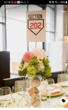 a baseball themed centerpiece sits atop a table with wine glasses, plates and utensils