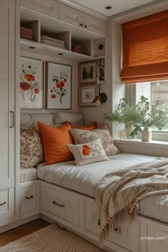 a white bed sitting under a window next to a wooden floor covered in lots of pillows