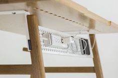 an electronic device is plugged into the side of a wooden table with wires attached to it