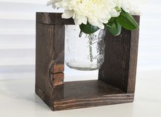 a vase filled with white flowers sitting on top of a wooden block