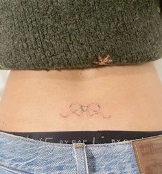 a woman's stomach with a small bow tattoo on her lower back side ribcage