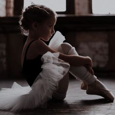 a young ballerina sitting on the floor with her legs crossed