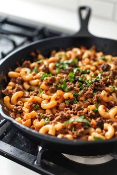 a skillet filled with pasta and ground beef on top of an oven burner