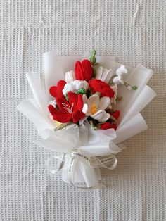 a red and white flower bouquet on top of a bed