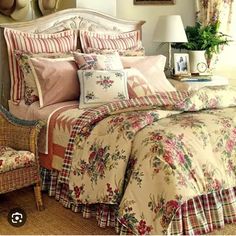 a bed with floral comforter and pillows on top of it in a bedroom next to a chair